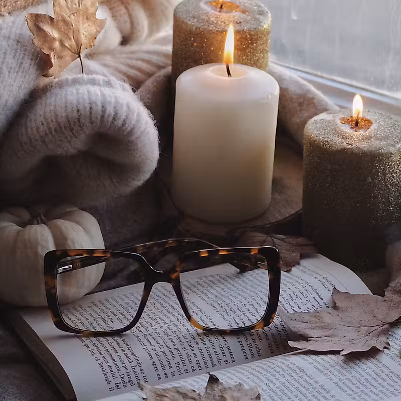 bougies, un livre ouvert et des feuilles d'automne sur un rebord de fenêtre