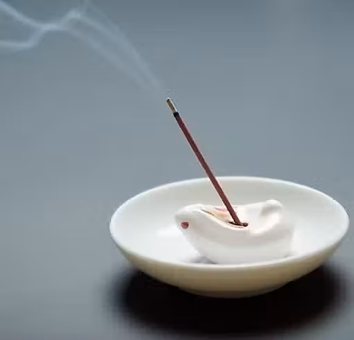 un bâton d'encens dans un bol blanc avec de la fumée qui s'en échappe