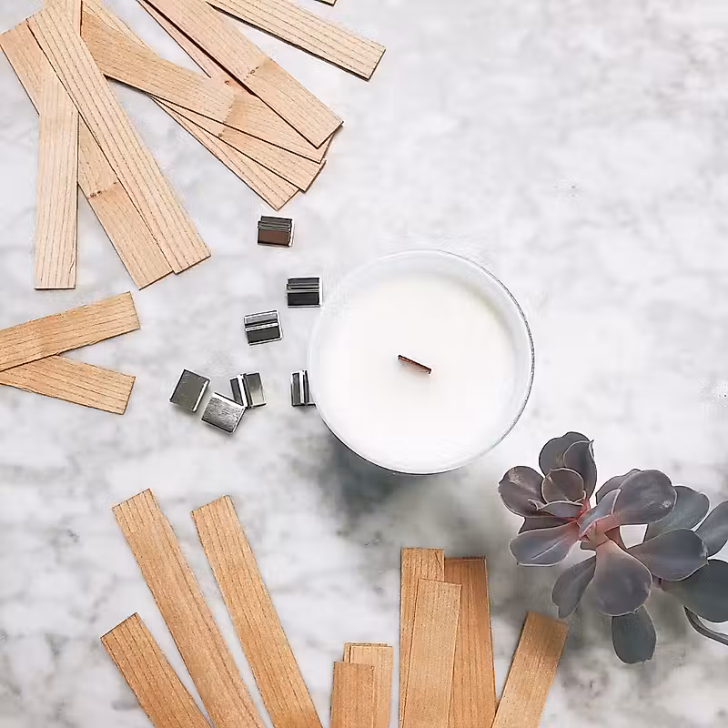 bâtonnets en bois et une bougie sur un comptoir en marbre