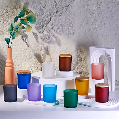 various colored candles sit on a shelf next to a vase