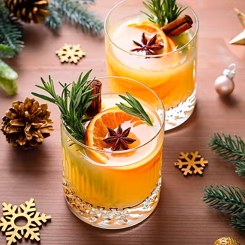 deux verres de jus d'orange et des épices sur une table en bois