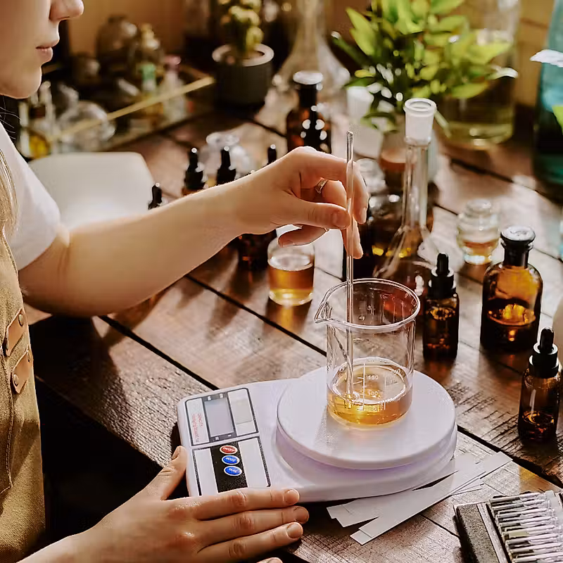 Une personne en tablier utilise une balance pour mesurer la quantité de liquide dans un verre